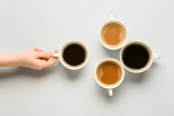 Mão feminina e xícaras de café no fundo claro - Foto, Imagem