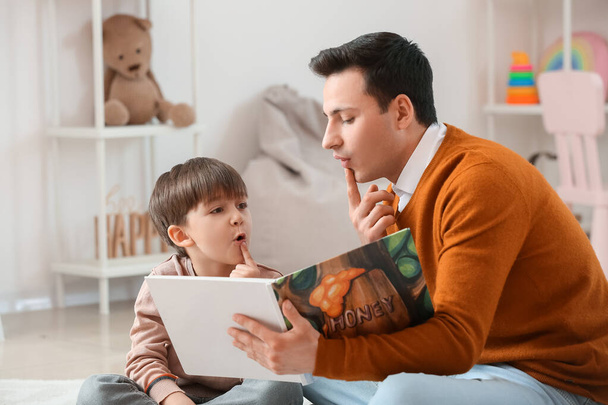 Речевой терапевт с маленьким мальчиком, читающим книги в офисе - Фото, изображение