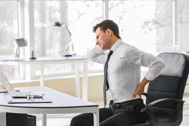 Молодой человек страдает от болей в спине в офисе - Фото, изображение