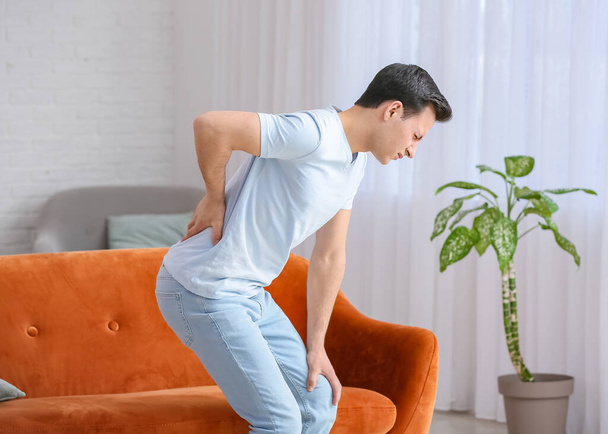 Young man suffering from back pain at home - Fotoğraf, Görsel