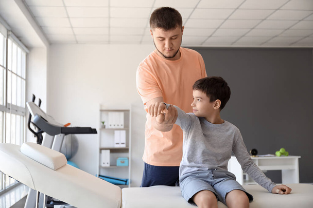 Physiotherapist working with boy in rehabilitation center - Foto, afbeelding