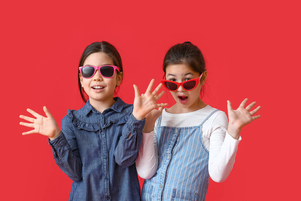 Stylish little sisters on color background - Foto, afbeelding