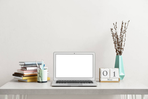 Рабочее пространство с современным ноутбуком у светлой стены в офисе - Фото, изображение