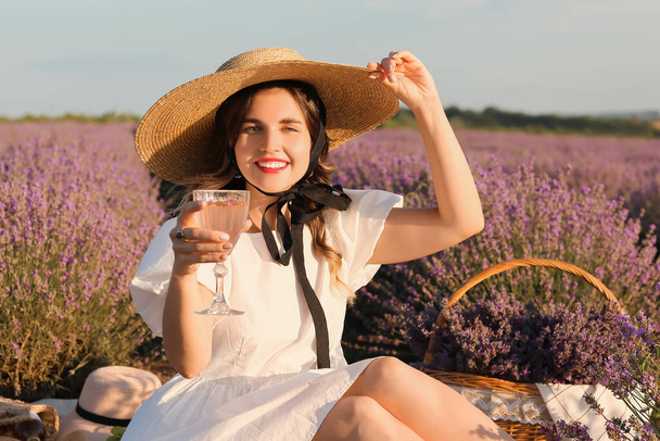 Beautiful young woman having picnic in lavender field - Photo, Image