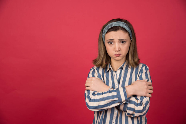 Young girl standing with arms crossed on red background. High quality photo - 写真・画像