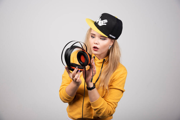 Portrait of young woman in hoodie posing with a stylish cap and headphones . High quality photo - Φωτογραφία, εικόνα