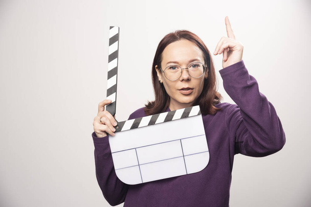 Young woman posing with a cinema tape on a white background . High quality photo - Foto, afbeelding