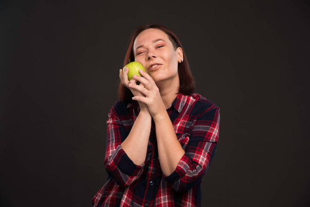 Female model in fall winter collection outfits holding a green apple and feeling happy. High quality photo - Photo, Image