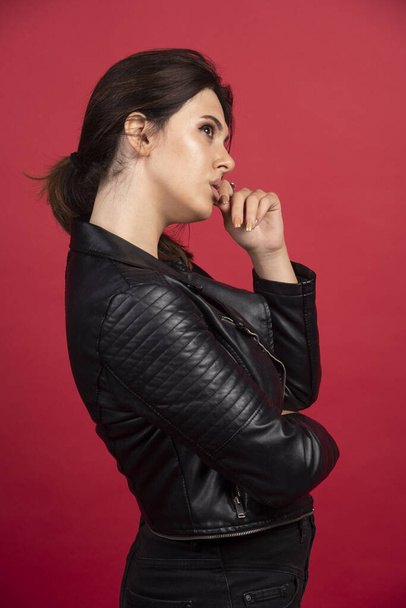 Cool girl in black leather jacket puts her finger to her chin and thinking. High quality photo - Фото, зображення