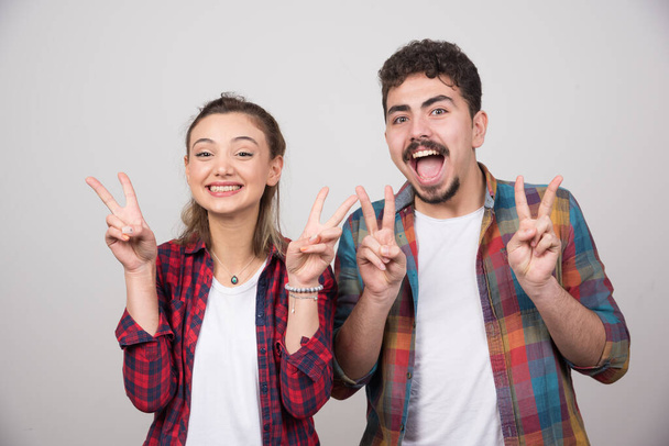 Beautiful couple together wearing plaid shirt over smiling with happy face doing victory sign. High quality photo - Foto, Imagem