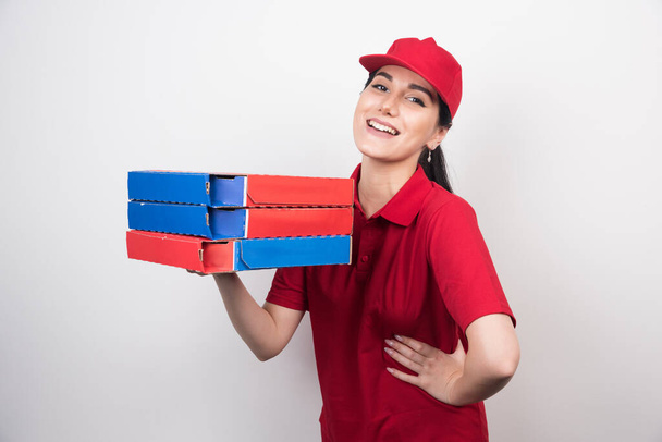 Mensajería femenina que lleva cajas de pizza sobre fondo blanco - Foto, Imagen