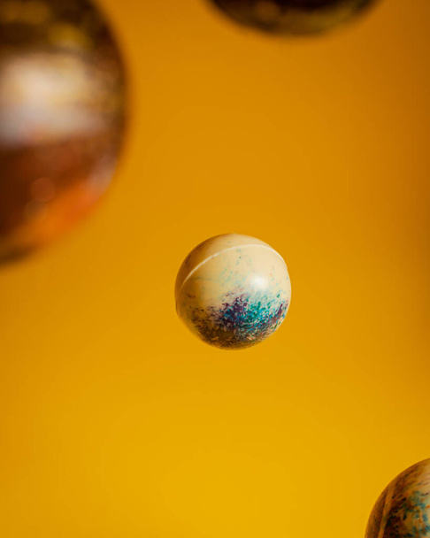 A selective closeup of rubber balls in the air on a yellow background - Фото, изображение