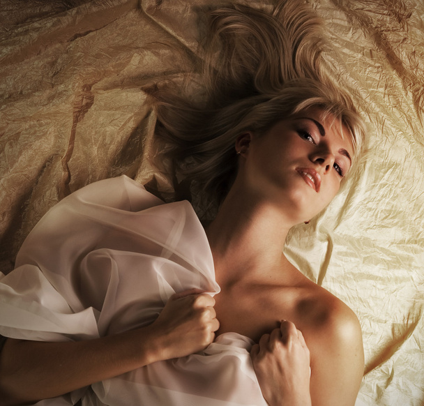 Portrait of a lovely beautiful blond girl lying in a bed - Fotoğraf, Görsel