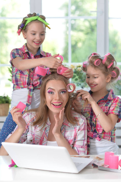 Cute  tweenie girls and mother  in hair curlers  with laptop at home - Fotoğraf, Görsel