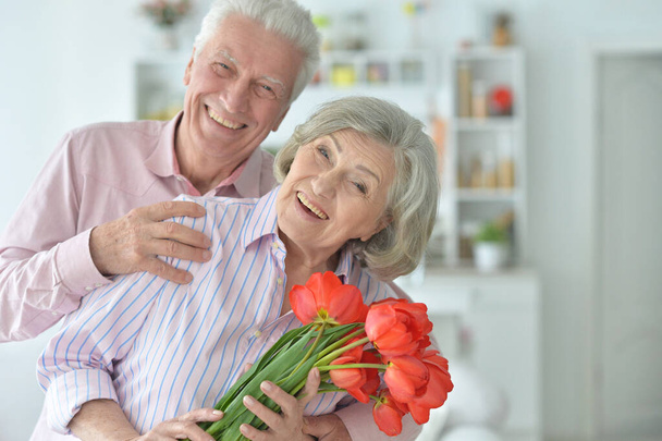 Happy senior couple at home with flowers - Фото, зображення