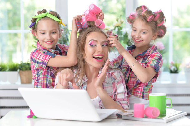 Cute  tweenie girls and mother  in hair curlers  with laptop at home - Photo, Image