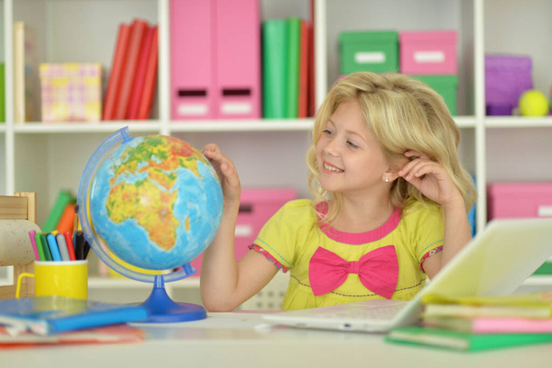 cute  girl  with globe sitting  at desk - Foto, afbeelding