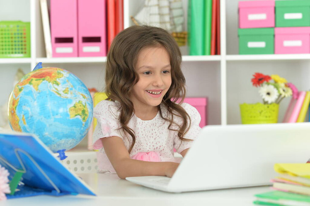 Cute little girl ding home work at desk - Zdjęcie, obraz
