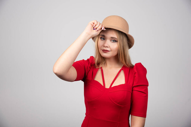 Joven mujer hermosa en vestido rojo tocando su sombrero. Foto de alta calidad - Foto, Imagen