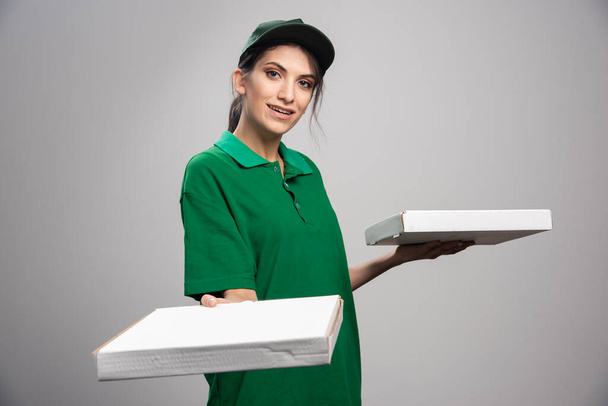 Mulher de entrega segurando caixas de pizza no fundo cinza. Foto de alta qualidade - Foto, Imagem