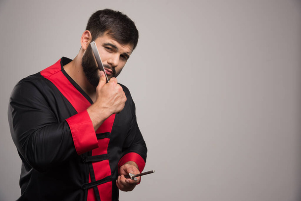 Thoughtful man with beard holding a sharp knife. High quality photo - Foto, afbeelding