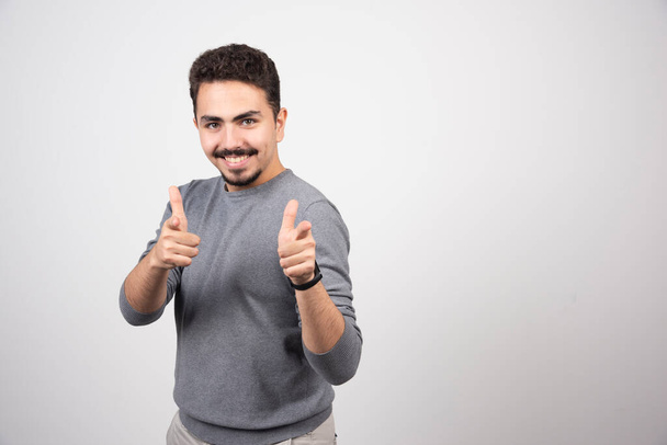 Smiling man showing thumbs up and looking at camera. High quality photo - Foto, Imagem