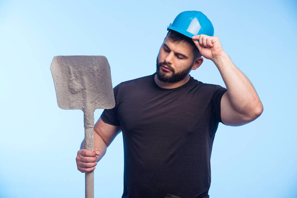Trabalhador da construção com capacete azul segurando o equipamento. Foto de alta qualidade - Foto, Imagem