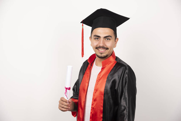 Gelukkige mannelijke student met diploma poseren op witte achtergrond. Hoge kwaliteit foto - Foto, afbeelding