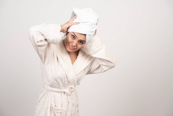 Kaunis nuori nainen valkoisessa kylpytakissa eristettynä valkoisella taustalla. Laadukas kuva - Valokuva, kuva