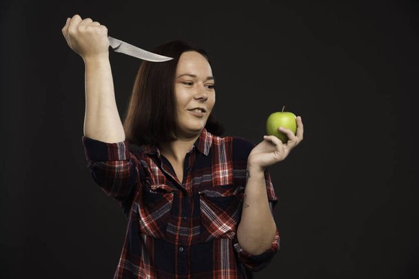 Жіноча модель восени зимового одягу накладає ніж на зелене яблуко. Високоякісна фотографія
 - Фото, зображення