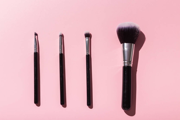 Various make-up brushes on pink background, top view. Cosmetics and beauty concept. - Photo, image