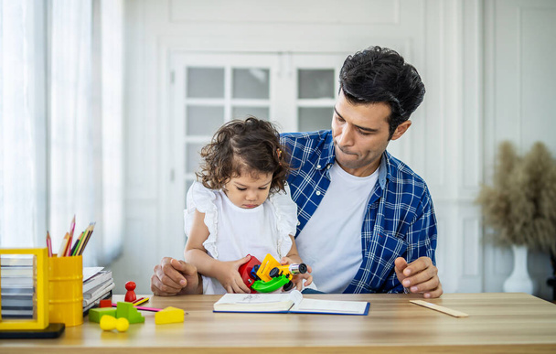 család, apaság és gyermekkor koncepció - boldog apa és kislány játszik játék mikroszkóppal otthon az asztalnál - Fotó, kép
