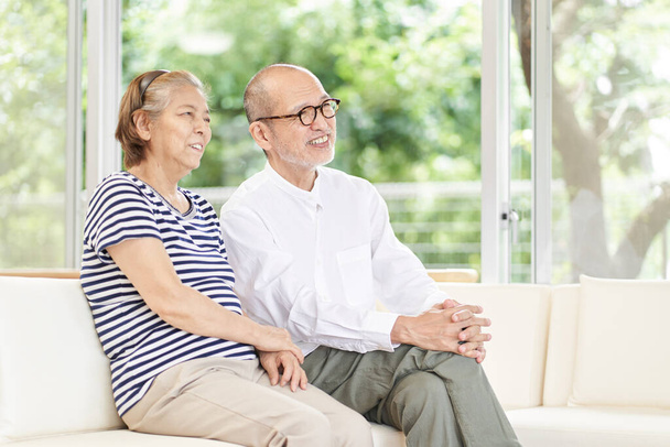 Älteres Paar sitzt auf der Couch und unterhält sich - Foto, Bild