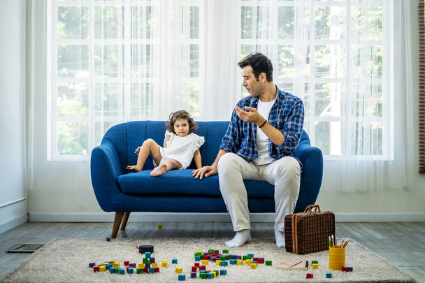 Νεαρός ελκυστικός πατέρας μιλάει με τη μικρή χαριτωμένη κόρη του μετά το παιχνίδι με ξύλινα μπλοκ, ευτυχισμένη οικογένεια ξοδεύουν ελεύθερο χρόνο το Σαββατοκύριακο μαζί - Φωτογραφία, εικόνα