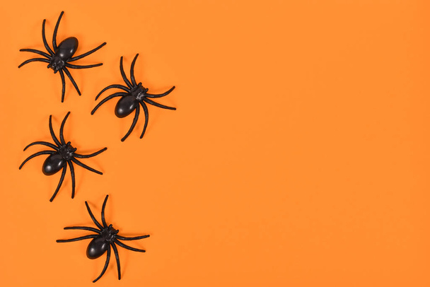 Plastic spiders on side of bright orange Halloween background with empty copy space - Foto, Imagem
