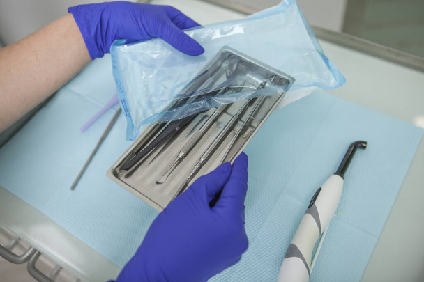 Close up of dentists hands unpacking sterile instruments for teeth examination - Foto, afbeelding