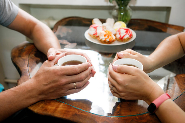 Romantic background, two cups of coffee and hands of couple in love on date. Romantic dinner in valentine's day - Foto, Bild
