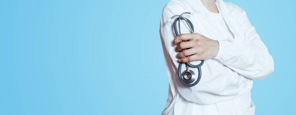 Doctor vestido blanco uniforme con estetoscopio en las manos fondo azul. medición del cardiólogo. Concepto de atención sanitaria y tratamiento - Foto, imagen