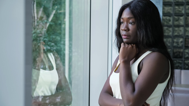 Verontruste Afro-Amerikaanse vrouw in de buurt van raam thuis - Foto, afbeelding