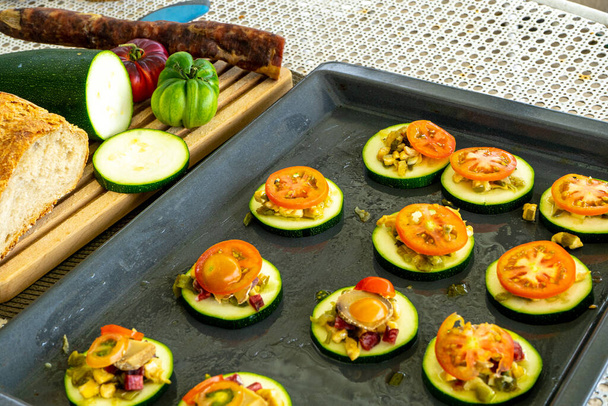 sliced tray of zucchini with tomato and a mince of vegetables and pieces of baking sausage - Photo, Image