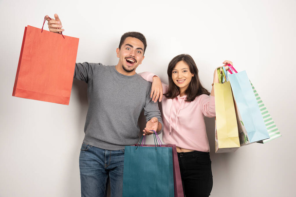 Glückliches Paar mit Einkaufstaschen, die auf weißem Hintergrund posieren. Hochwertiges Foto - Foto, Bild