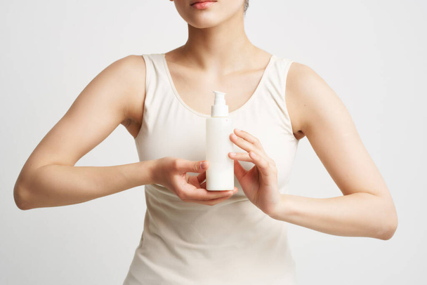 Frau im weißen T-Shirt mit Lotion Gesunde Hautkosmetik - Foto, Bild