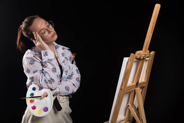 Woman posing with brushes and canvas on black background . High quality photo - Fotó, kép