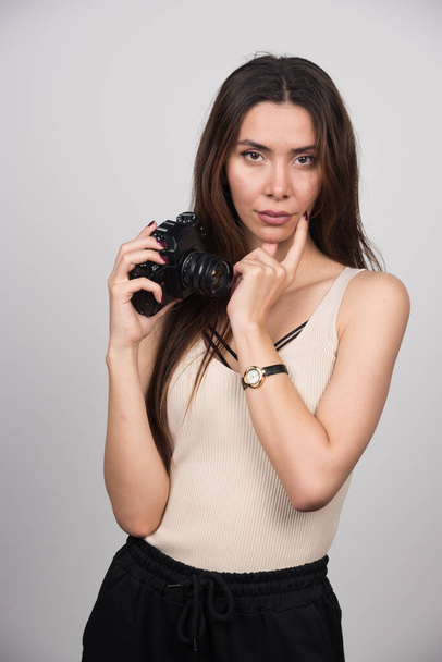 Beautiful woman holding camera and posing on gray background. High quality photo - Foto, imagen