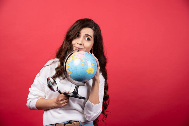 Happy woman posing with globe and magnifying glass. High quality photo - Foto, immagini