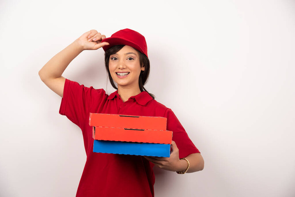Gelukkige vrouwelijke pizzabezorger op witte achtergrond met drie kartonnen pizza. Hoge kwaliteit foto - Foto, afbeelding