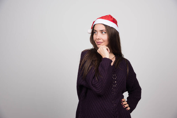 Joven mujer hermosa en Santa sombrero posando sobre fondo gris. Foto de alta calidad - Foto, imagen
