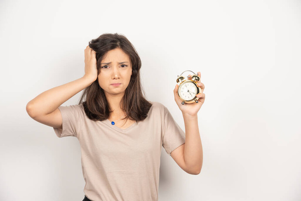Young woman holding alarm clock on white background . High quality photo - Foto, Bild
