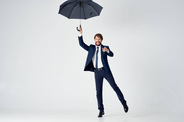 business man in a suit holding an umbrella elegant style protection from the rain - 写真・画像