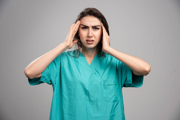 Female doctor having headache on gray background. High quality photo - Foto, Imagem